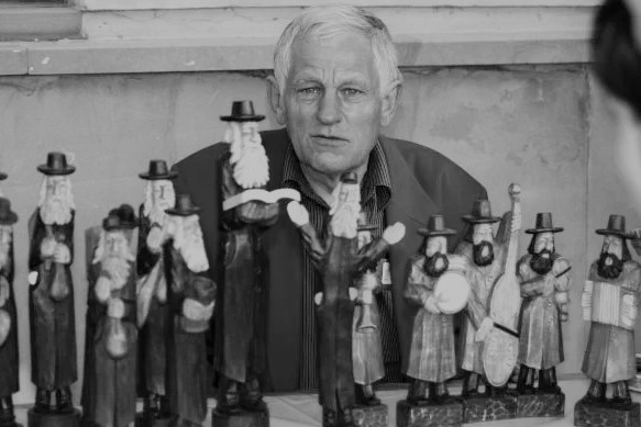 Czarno-biała fotografia Romana Matuszewskiego. Przed mężczyzną stoją rzeźby.