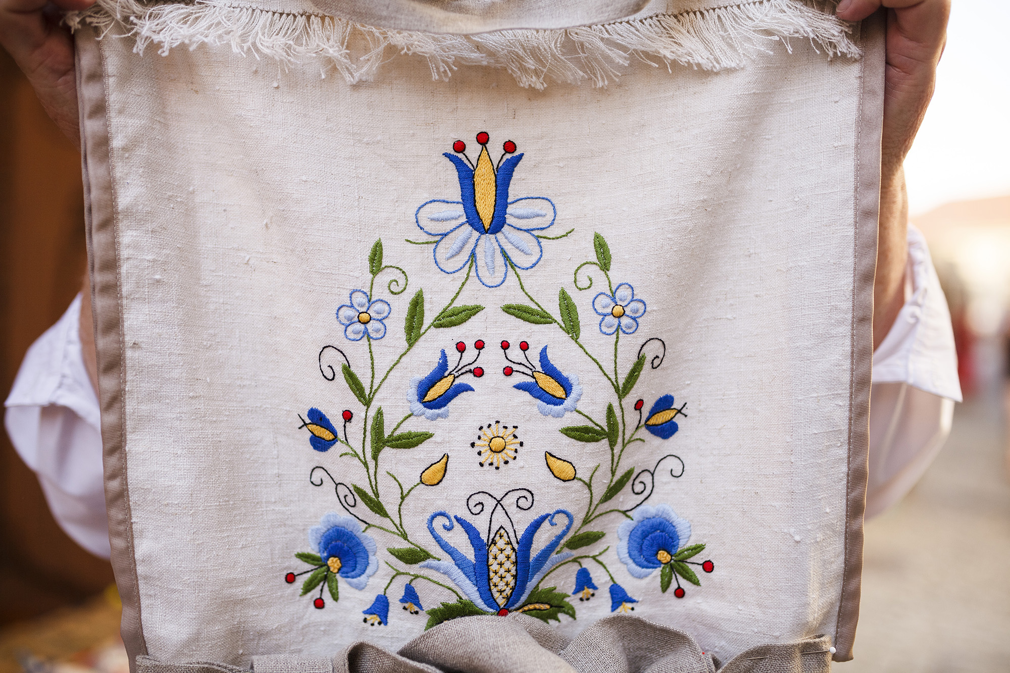 An embroidered linen table mat with a blue floral motif