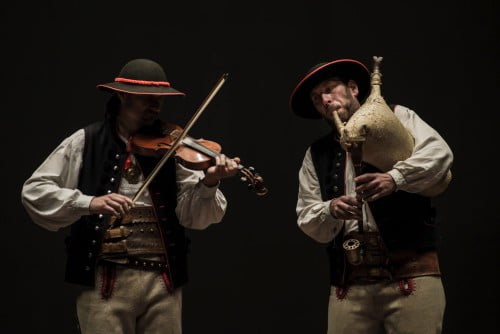 Z ciemnej sceny wyłaniają się postaci dwóch muzyków z kapeli Ficek/Blachura. Mężczyźni są ubrani w tradycyjne stroje żywieckie - białe koszule, czarne kamizelki, duże, zdobne skórzane pasy, jasne wełniane spodnie i czarne kapelusze. Mężczyźni grają na skrzypcach i dudach.