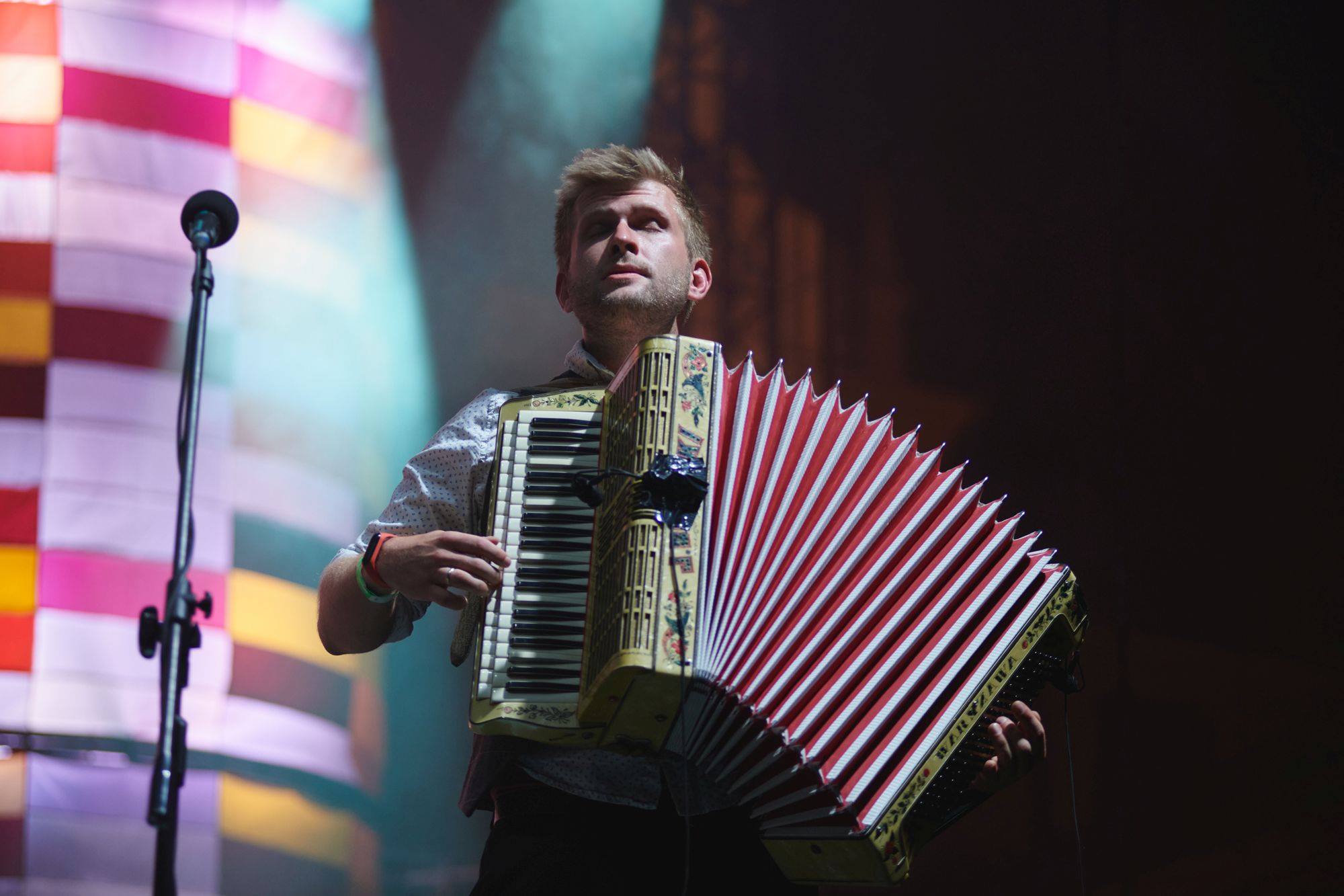 Na zdjęciu Mateusz Wachowiak z WoWaKin Trio. Mężczyzna stoi na scenie, ma zamknięte oczy, gra na akordeonie.