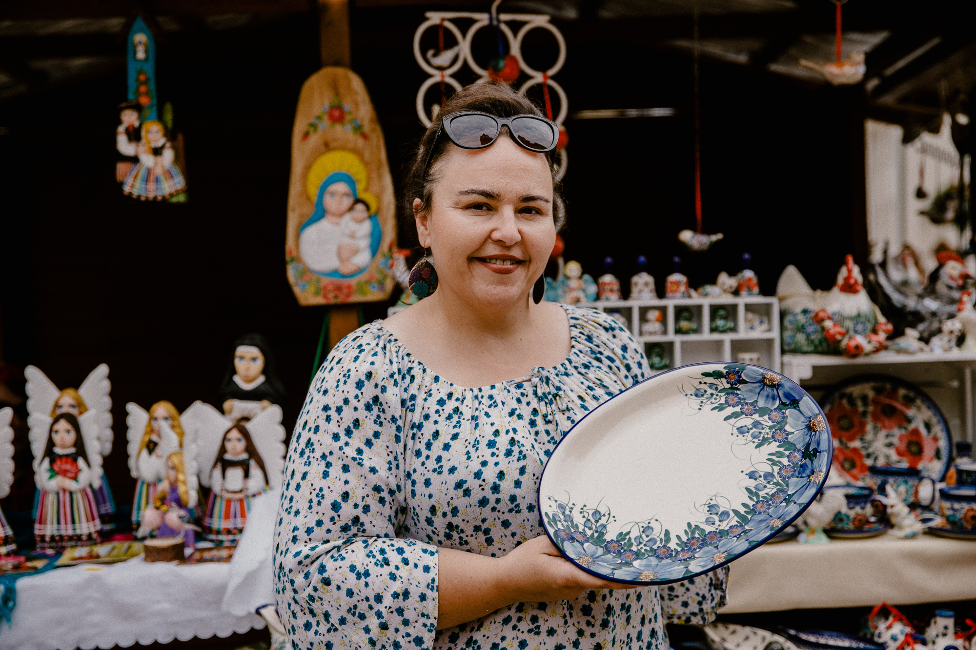 Beata Woźniak trzyma w ręce własnoręcznie zrobiony talerz ceramiczny z namalowanymi kwiatami.