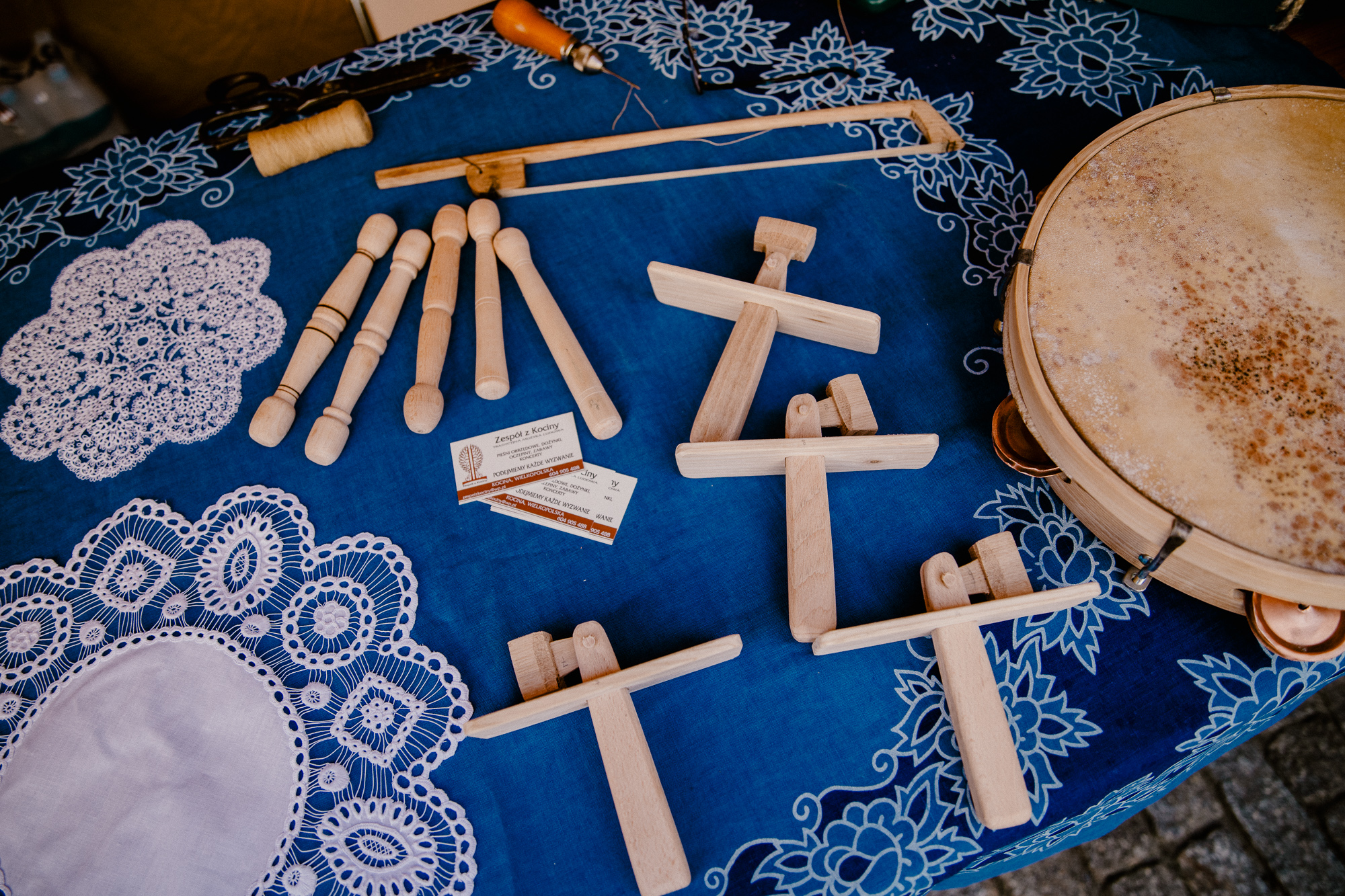 Drewniane instrumenty: tamburyno i kołatki oraz zrobione na szydełku serwetki.