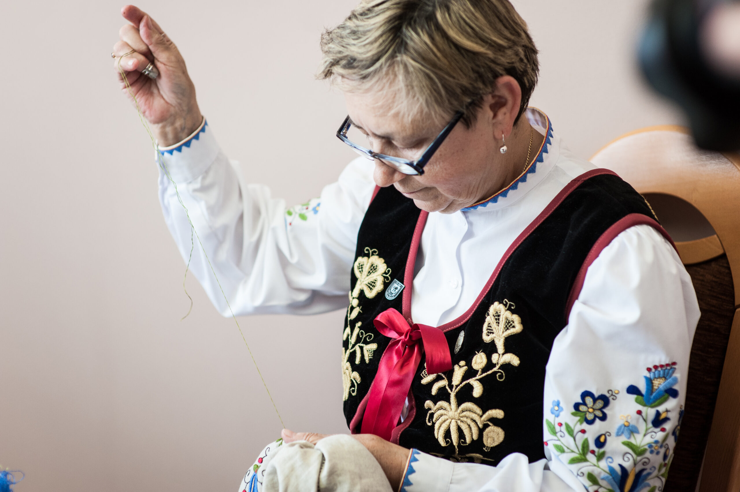 Bernadetta Reglińska w stroju ludowym, haftująca kolejne dzieło.