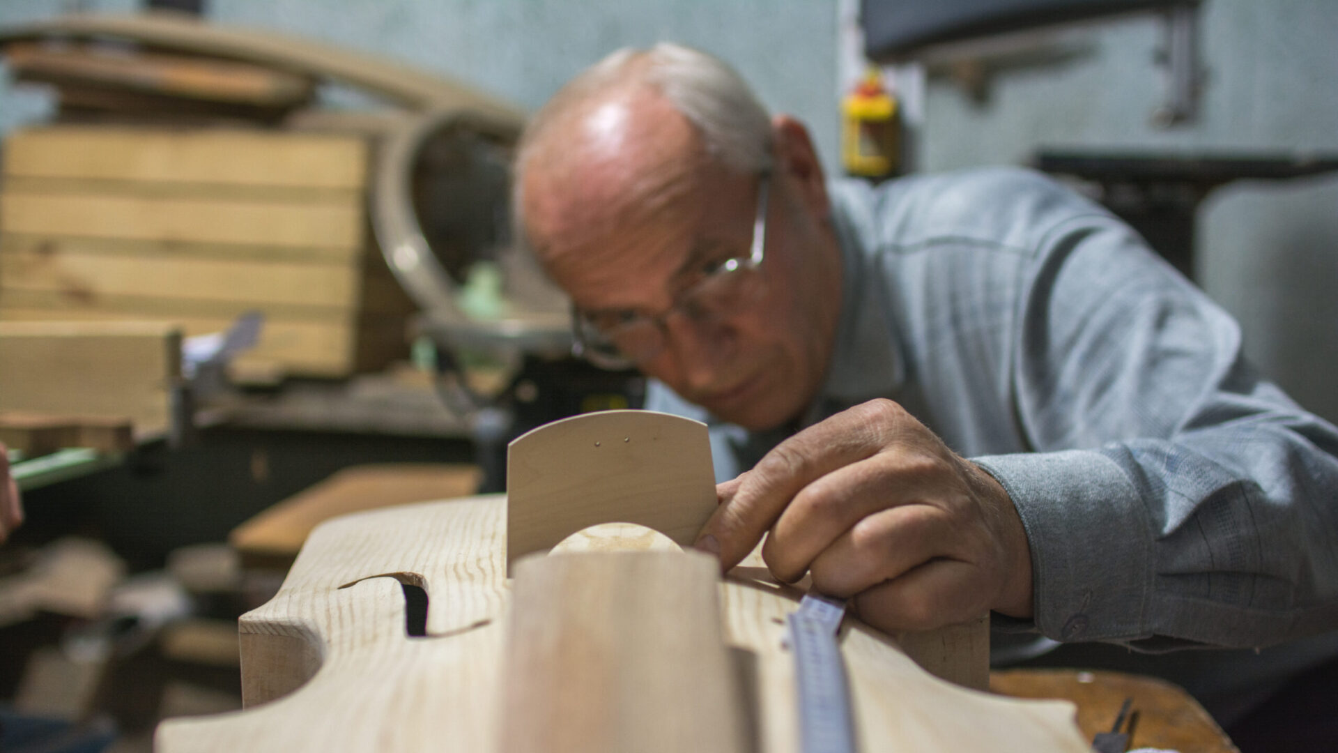 Mężczyzna rzeźbi w drewnianym instrumencie.