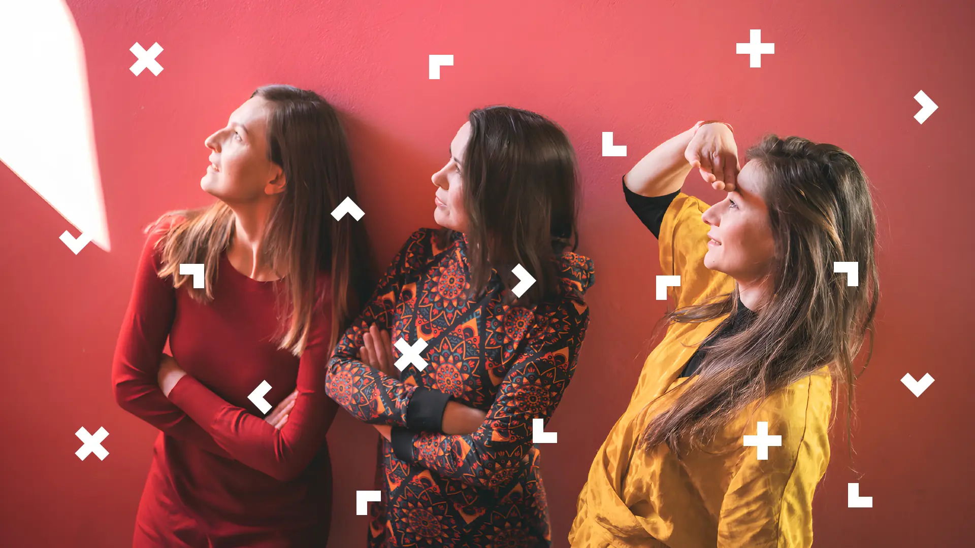 Trzy kobiety stoją pod ścianą i patrzą w lewo.