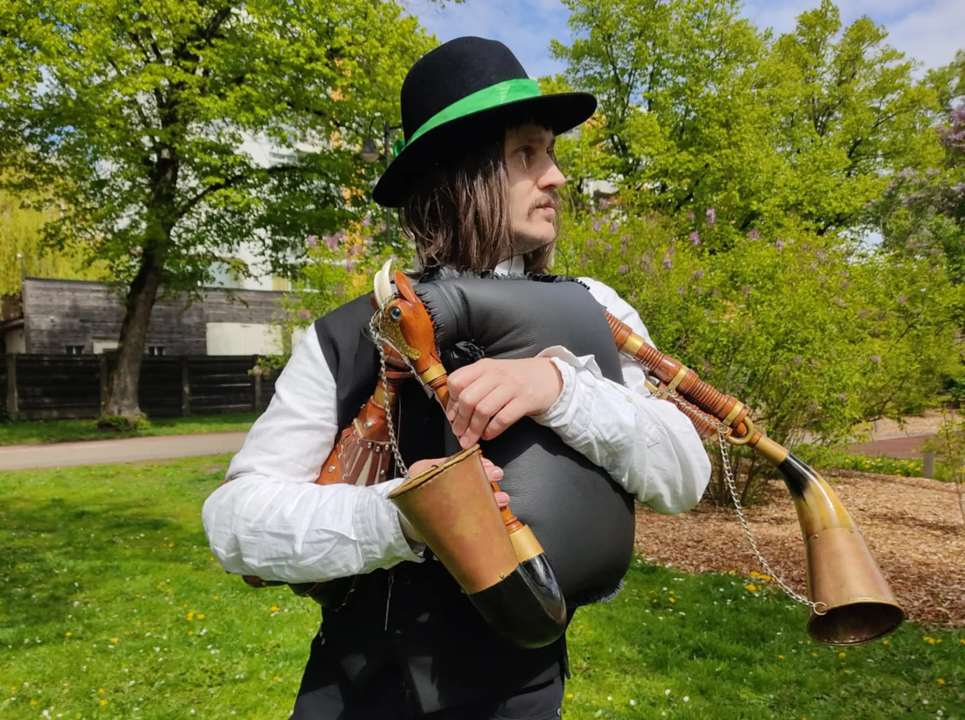 Mężczyzna trzyma w ręce dwie dudy. Jest ubrany na ludowo.