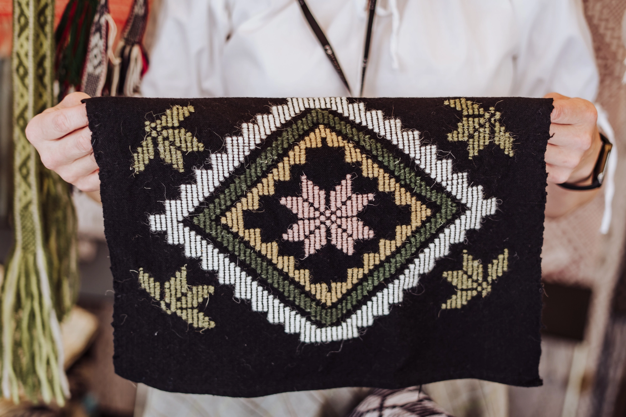 Kobieta trzyma w ręce haftowaną poszewkę.