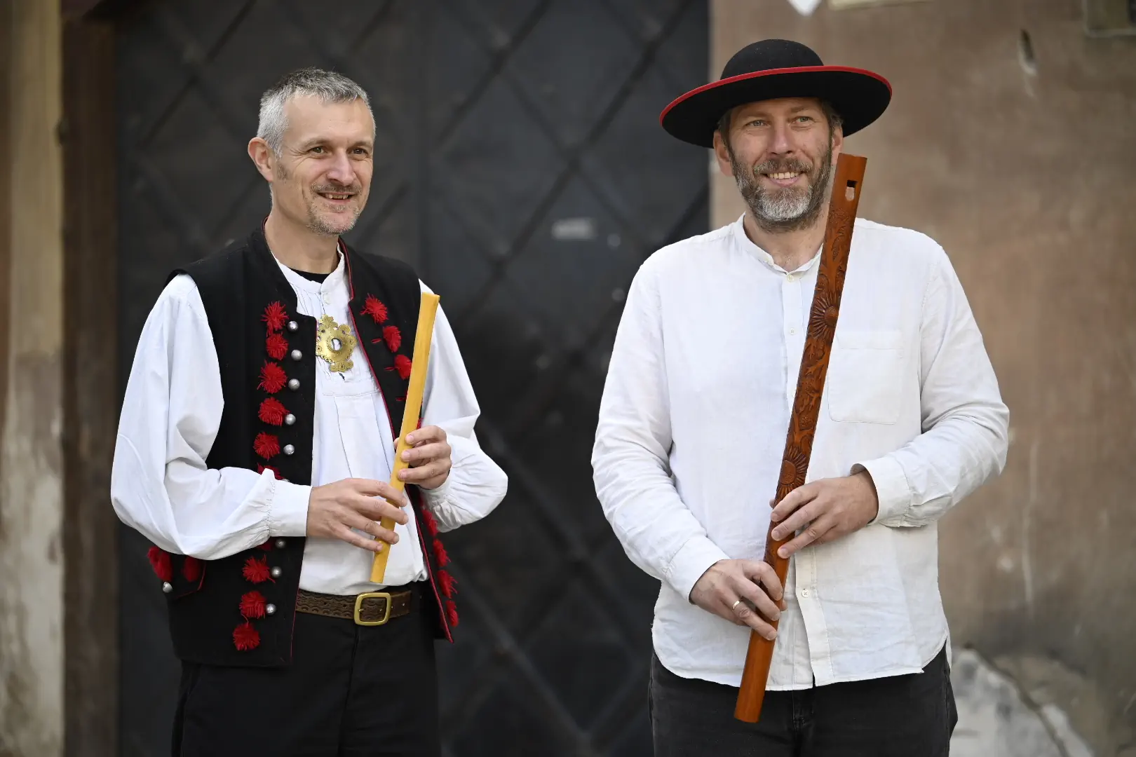 Dwaj mężczyźni trzymają w rękach drewniane gwizdki.