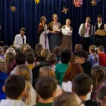 Sala pełna dzieci. Trwa koncert kolęd. Artyści śpiewają.