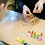 Dłonie związują małą konstrukcję ze słomy. To ozdoba nazywana pająkiem.