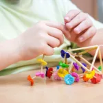 Chłopiec przywiązuje bibułowe ozdoby do pająka.