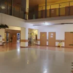 Wnętrze szkoły. Nad przestronnym korytarzem wisi podłaźniczka.