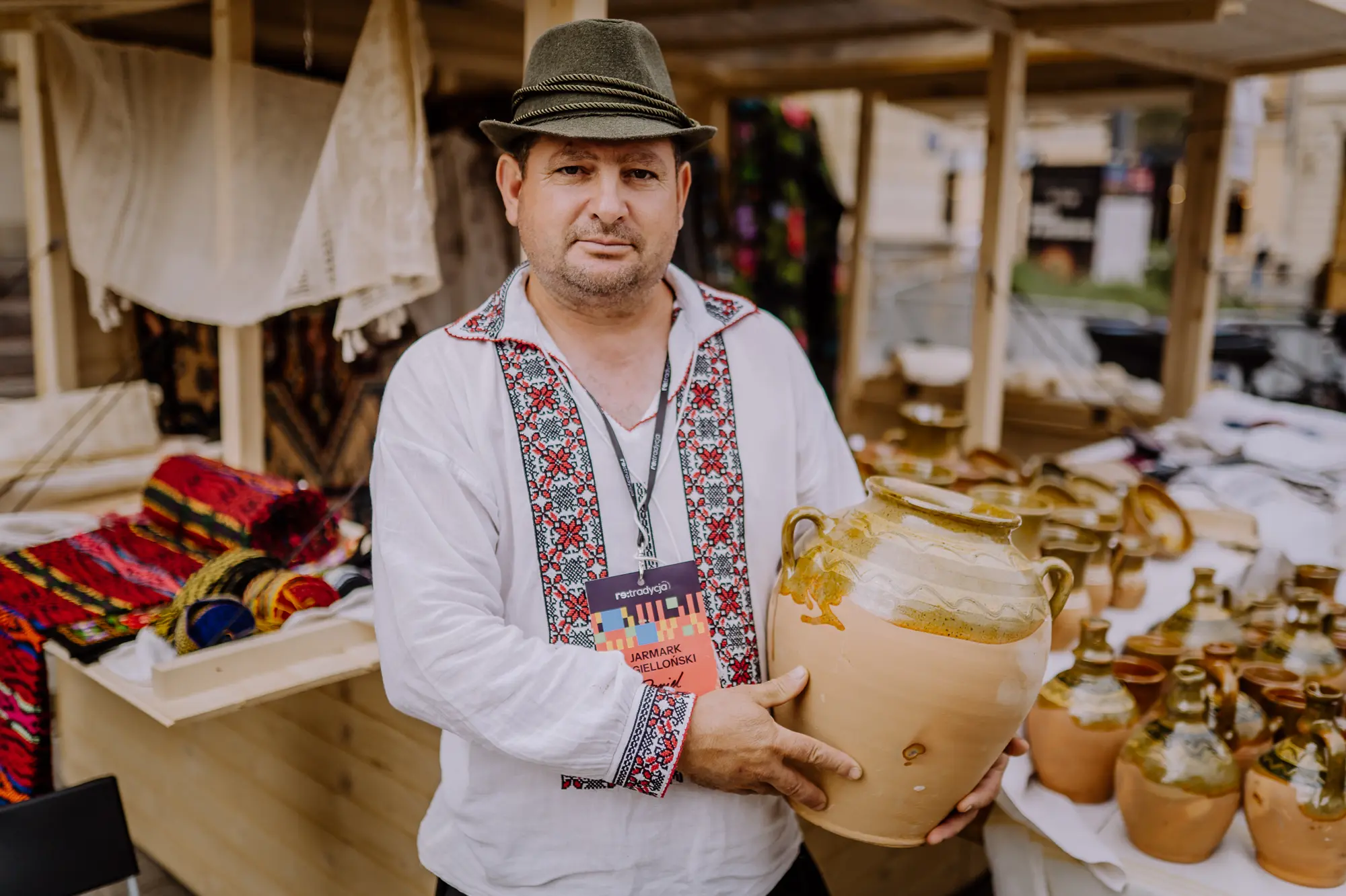 Portret twórcy. Mężczyzna trzyma w rękach olbrzymi, zielony dzban.