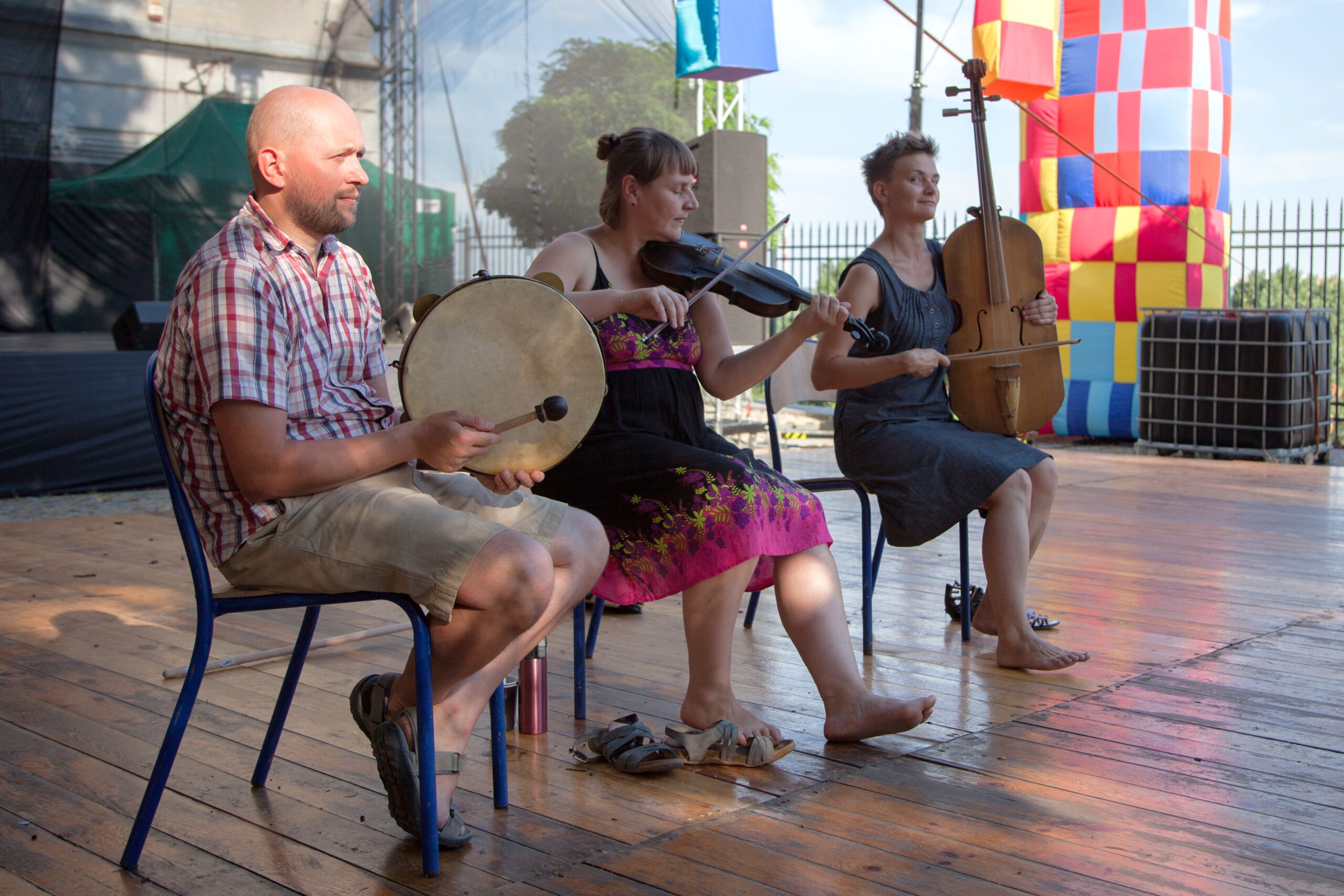 Dwie kobiety i mężczyzna grają na instrumentach na scenie.